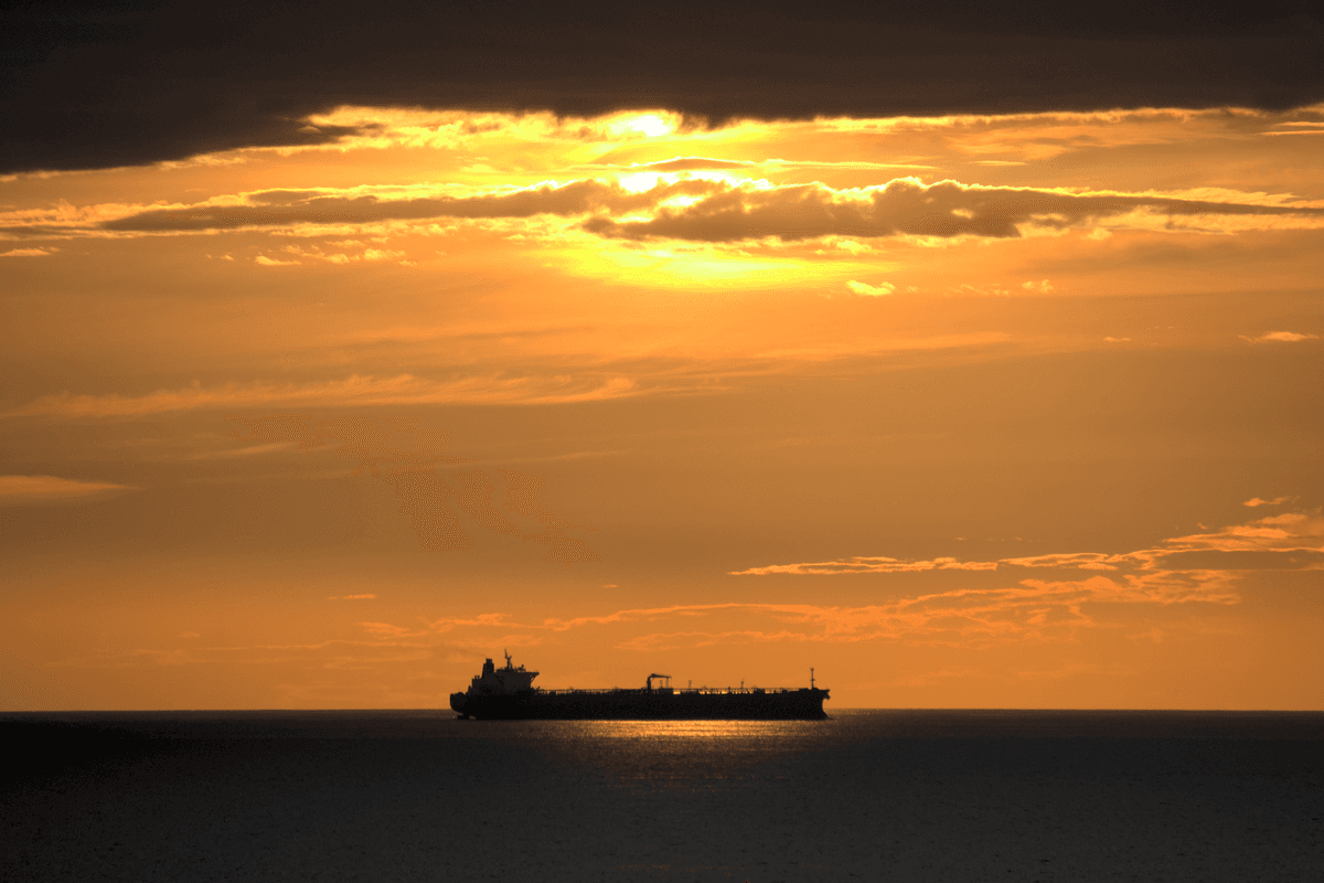 Cargo ship sailing into a golden sunset on the open ocean